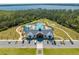 Aerial view of a community clubhouse with a pool, ample parking, and surrounded by trees and landscaping at 6667 Alder Rd, Harmony, FL 34773