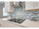 Close-up of modern kitchen features custom backsplash and sleek cooktop at 6667 Alder Rd, Harmony, FL 34773