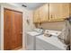 Cozy laundry room with white washer and dryer, wood door, and ample cabinet space for storage at 825 Second St, Orange City, FL 32763