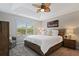 Spacious bedroom with a tray ceiling, ceiling fan, and large window overlooking the neighborhood at 9478 Silver Buttonwood St, Orlando, FL 32832