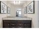 Bright bathroom featuring double sinks with granite countertops, dark cabinets, and modern artwork at 15980 Cape Coral Loop, Clermont, FL 34714