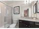 Well-lit bathroom featuring a glass shower, toilet, granite countertop, and dark wood cabinetry at 15980 Cape Coral Loop, Clermont, FL 34714
