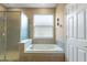 Bright bathroom featuring a large soaking tub with tile surround and frosted window at 9244 Pecky Cypress Way, Orlando, FL 32836