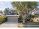 Well-maintained two-story home with mature trees, a two-car garage, and a tidy front yard at 9244 Pecky Cypress Way, Orlando, FL 32836