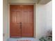 Close-up of the double front doors, featuring paneled detailing, a bronze handle, and a smart lock system at 9244 Pecky Cypress Way, Orlando, FL 32836