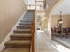 Spacious hallway with a carpeted staircase, tile flooring, and views into the dining room at 9244 Pecky Cypress Way, Orlando, FL 32836