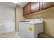 Functional laundry room with upper cabinets, a white washer and dryer, and a tile floor at 9244 Pecky Cypress Way, Orlando, FL 32836