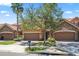 Townhome exterior with a two-car garage, stone accents, tile roof, and a landscaped front yard with mature trees at 10743 Belfry Cir, Orlando, FL 32832