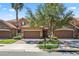 Townhome exterior with a two-car garage, stone accents, tile roof, and a landscaped front yard with mature trees at 10743 Belfry Cir, Orlando, FL 32832
