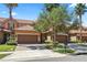 Townhome exterior with a two-car garage, stone accents, tile roof, and a landscaped front yard with palm trees at 10743 Belfry Cir, Orlando, FL 32832