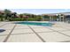 Community pool area with a rectangular pool, surrounding patio, lounge chairs, and a shade structure overlooking a lake at 10743 Belfry Cir, Orlando, FL 32832