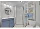 Compact bathroom with glass enclosed shower, blue vanity, and shelving unit at 1110 Virginia Ave, St Cloud, FL 34769