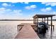 Wooden dock with a covered boat lift and a boat, extending into a calm lake under a partly cloudy sky at 12228 Kirby Smith Rd, Orlando, FL 32832