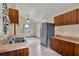 Well-lit kitchen with stainless steel refrigerator, neutral tile floors, wooden cabinets, and a double sink at 12228 Kirby Smith Rd, Orlando, FL 32832