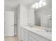 Bright bathroom featuring double sinks, quartz countertops, and a large mirror with vanity lighting at 1324 Painted Bunting Ave, Oakland, FL 34787