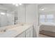 Well-lit bathroom vanity with double sinks, quartz countertops, and view into the bright primary bedroom at 1324 Painted Bunting Ave, Oakland, FL 34787
