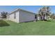 View of the backyard featuring green lawn and a home's exterior with white siding at 1461 Sothell St, The Villages, FL 32162