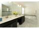 Bathroom featuring double sinks, white countertop, soaking tub, and glass enclosed shower at 1577 Mulligan Blvd, Davenport, FL 33896