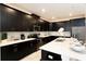 Modern kitchen with black cabinets, white countertops, stainless steel appliances, and breakfast bar at 1577 Mulligan Blvd, Davenport, FL 33896