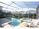 Inviting pool and spa surrounded by a screened-in lanai and manicured greenery at 1577 Mulligan Blvd, Davenport, FL 33896