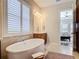 Bright bathroom showcasing a soaking tub beneath shuttered windows with an open doorway to the bedroom at 16675 Otterchase Ln, Winter Garden, FL 34787