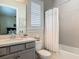 Bathroom features a gray vanity and shower-tub combination with a white curtain and matching gray tiling at 16675 Otterchase Ln, Winter Garden, FL 34787