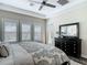 Well-lit bedroom with plantation shutters, dark wood floors, tray ceilings, and a dark dresser at 16675 Otterchase Ln, Winter Garden, FL 34787
