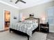 Well-lit bedroom featuring a ceiling fan, tray ceiling, wood floors, and open door to bathroom at 16675 Otterchase Ln, Winter Garden, FL 34787