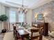 Elegant dining room with a tray ceiling, stone accent wall, and a chandelier over the wood dining table at 16675 Otterchase Ln, Winter Garden, FL 34787