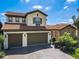 Beautiful two-story home with a red tile roof, brick driveway, three-car garage, and lush tropical landscaping at 16675 Otterchase Ln, Winter Garden, FL 34787
