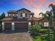 Beautiful two-story home with a red tile roof, brick driveway, three-car garage, and lush tropical landscaping at 16675 Otterchase Ln, Winter Garden, FL 34787
