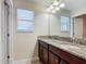 Bathroom featuring double sinks with granite countertops, wood cabinets, and a large mirror at 1671 Thetford Cir, Orlando, FL 32824