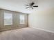 A well-lit bedroom with carpet flooring, a ceiling fan, and natural light from large windows at 1671 Thetford Cir, Orlando, FL 32824