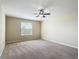 This neutral bedroom features carpet flooring, a ceiling fan, and a bright window at 1671 Thetford Cir, Orlando, FL 32824
