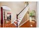 Inviting foyer with hardwood floors, a staircase with wooden handrail and red and brown patterned carpet on the steps at 2020 Corner Glen Dr, Orlando, FL 32820
