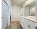 Modern bathroom with white dual vanity, framed mirror, glass-enclosed shower, and wood-look tile flooring at 2731 Forestdale St, St Cloud, FL 34771