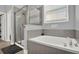 Bathroom featuring tiled walls, glass enclosed shower, and a separate soaking tub with a window view at 2795 Westyn Cove Ln, Ocoee, FL 34761