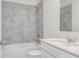 Modern bathroom features gray tiling surrounding a tub with a shower and a bright white sink and vanity at 3239 Laurent Loop, Davenport, FL 33837