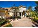 Elegant home with a stone facade and arched entrance, complemented by a brick driveway and lush landscaping at 4 Island Dr, Lake Mary, FL 32746