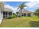 Spacious backyard with a well-kept lawn, palm trees, and access to the screened-in lanai at 433 Arcadia Lakes Dr, The Villages, FL 32162