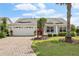 Charming single-story home with a well-manicured lawn, brick driveway, and a pop of color from the red front door at 433 Arcadia Lakes Dr, The Villages, FL 32162