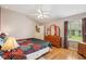 Cozy main bedroom with hardwood floors, neutral paint, and a large window overlooking the yard at 433 Arcadia Lakes Dr, The Villages, FL 32162
