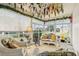 Inviting sunroom with white wicker furniture and bright, colorful hanging floral decorations at 433 Arcadia Lakes Dr, The Villages, FL 32162