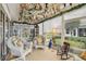 Bright sunroom with white wicker furniture and lush, decorative floral arrangements hanging from the ceiling at 433 Arcadia Lakes Dr, The Villages, FL 32162
