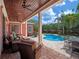 An outdoor covered patio area with wicker seating overlooking a pool and hot tub at 4350 New Broad St, Orlando, FL 32814