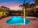 Beautiful kidney-shaped pool with a spa and travertine pavers in a private backyard setting with manicured landscaping and string lights at 4350 New Broad St, Orlando, FL 32814
