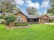 Beautiful brick home with a large window, flowering bushes, and a well-kept lawn, complemented by mature trees at 445 Songbird Way, Apopka, FL 32712