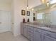 Bathroom features a double-sink vanity with granite countertop and large mirror at 6960 Audobon Osprey Cv, Harmony, FL 34773