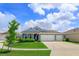 Charming single-story home featuring a manicured lawn and a three-car garage in a serene neighborhood at 6960 Audobon Osprey Cv, Harmony, FL 34773