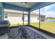 Enclosed patio with ceiling fan, grill, table and chairs overlooking green space and pond at 6960 Audobon Osprey Cv, Harmony, FL 34773
